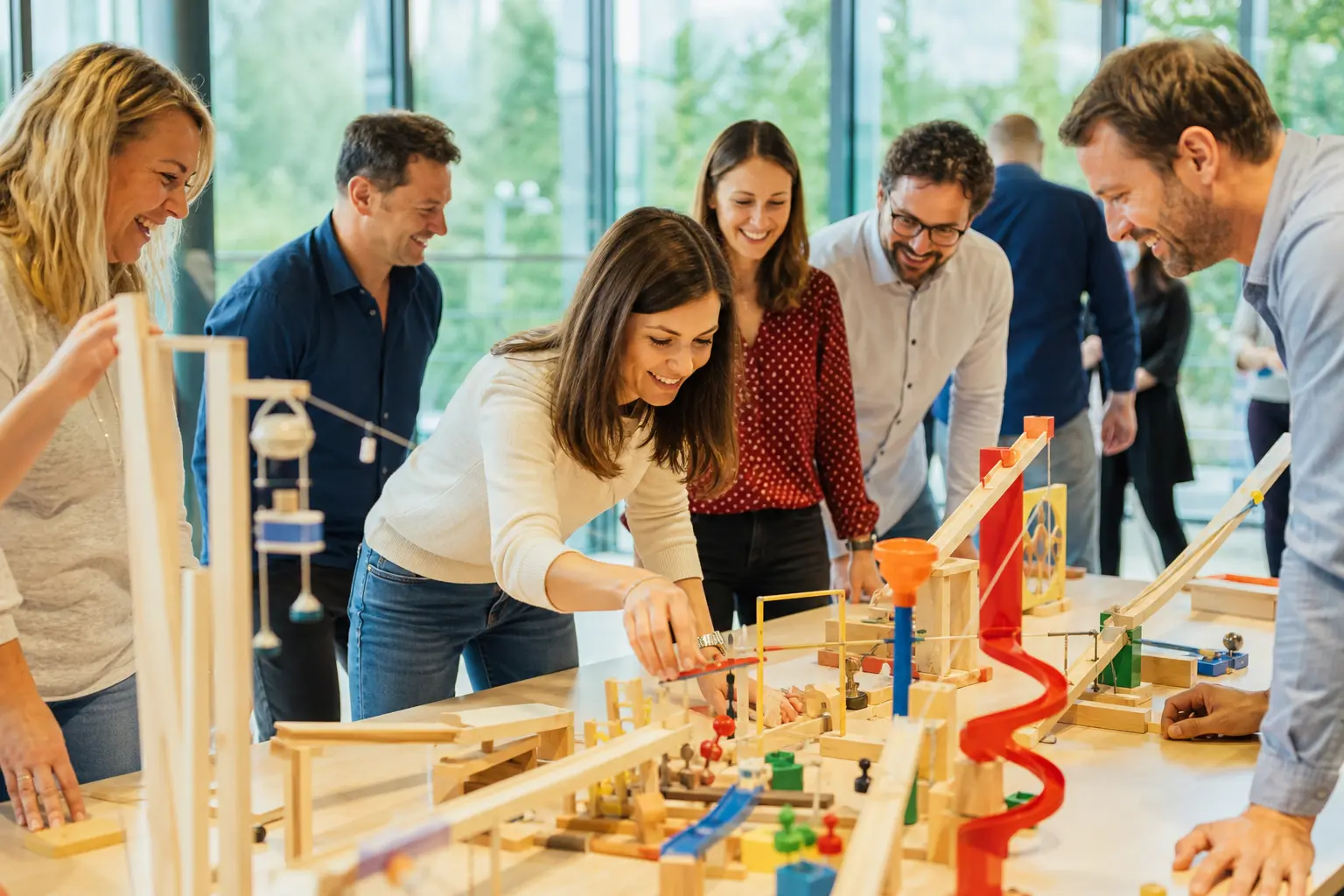 Collègues construisant ensemble un parcours de réaction en chaîne lors d’un atelier de team building en entreprise